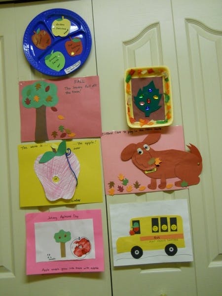 Children's artwork displayed on a door, including a blue plate with apple cutouts