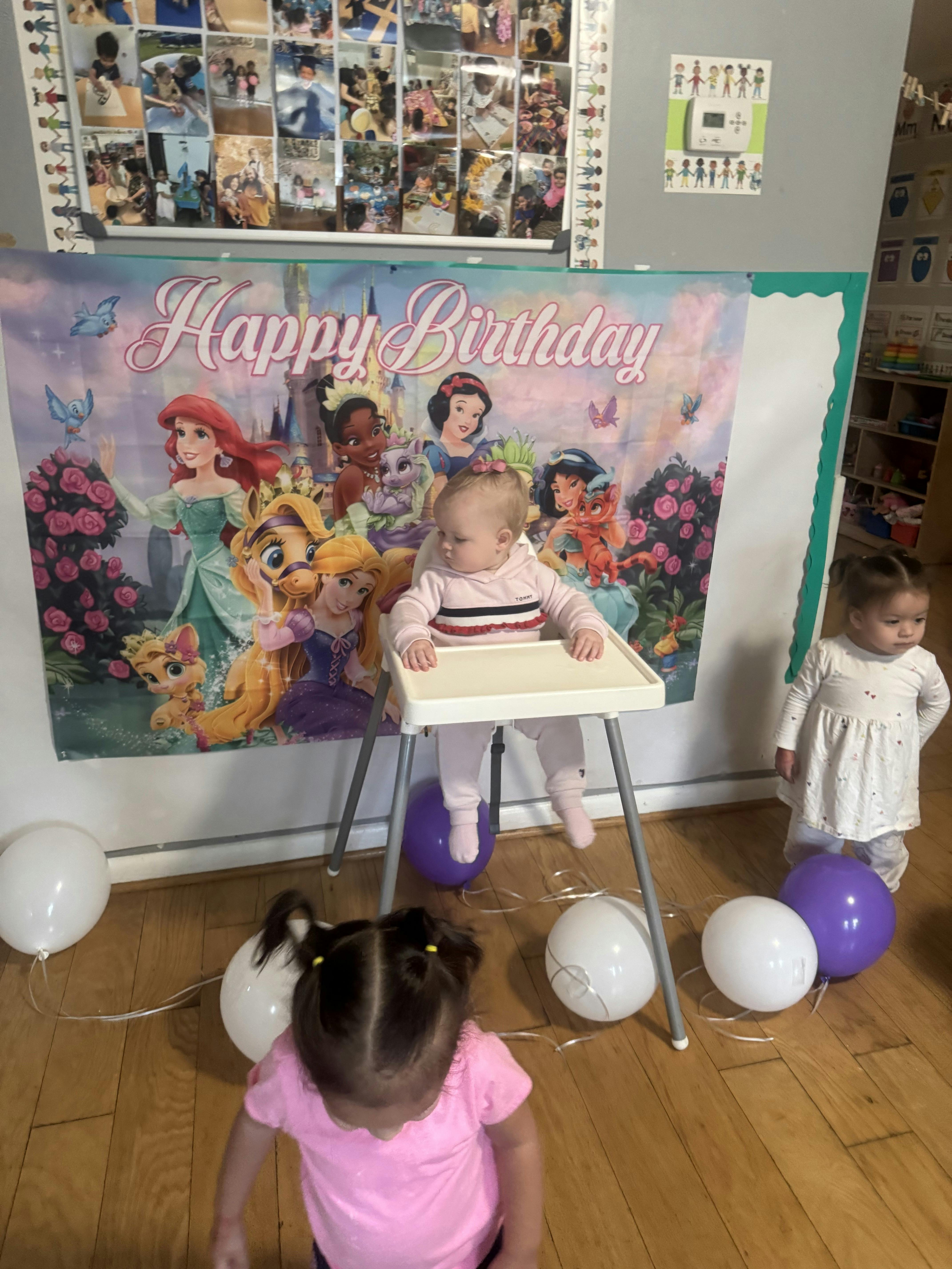 Child sitting in a high chair in front of a Happy Birthday banner