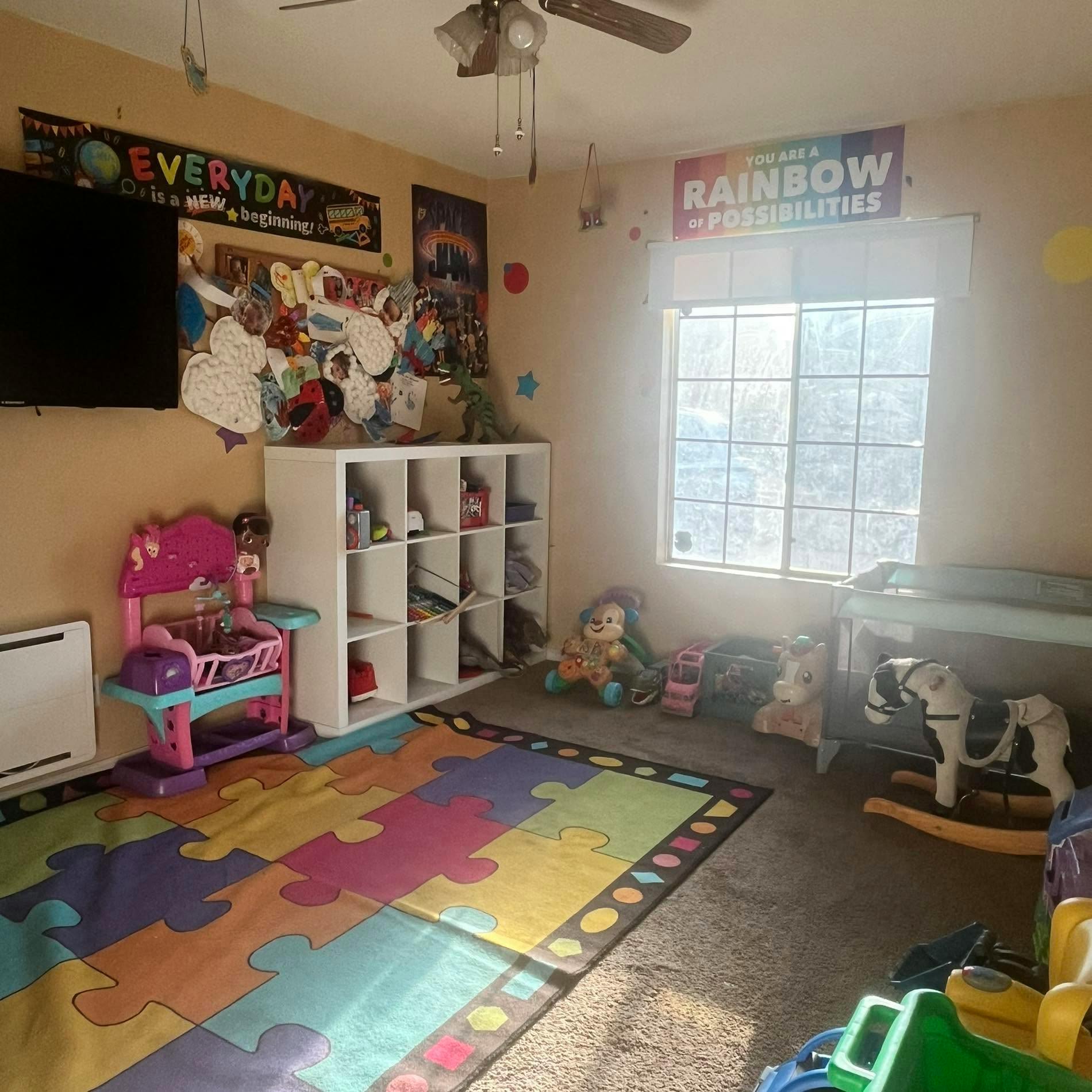 Child playroom with toy storage, a puzzle-patterned rug, and various toys