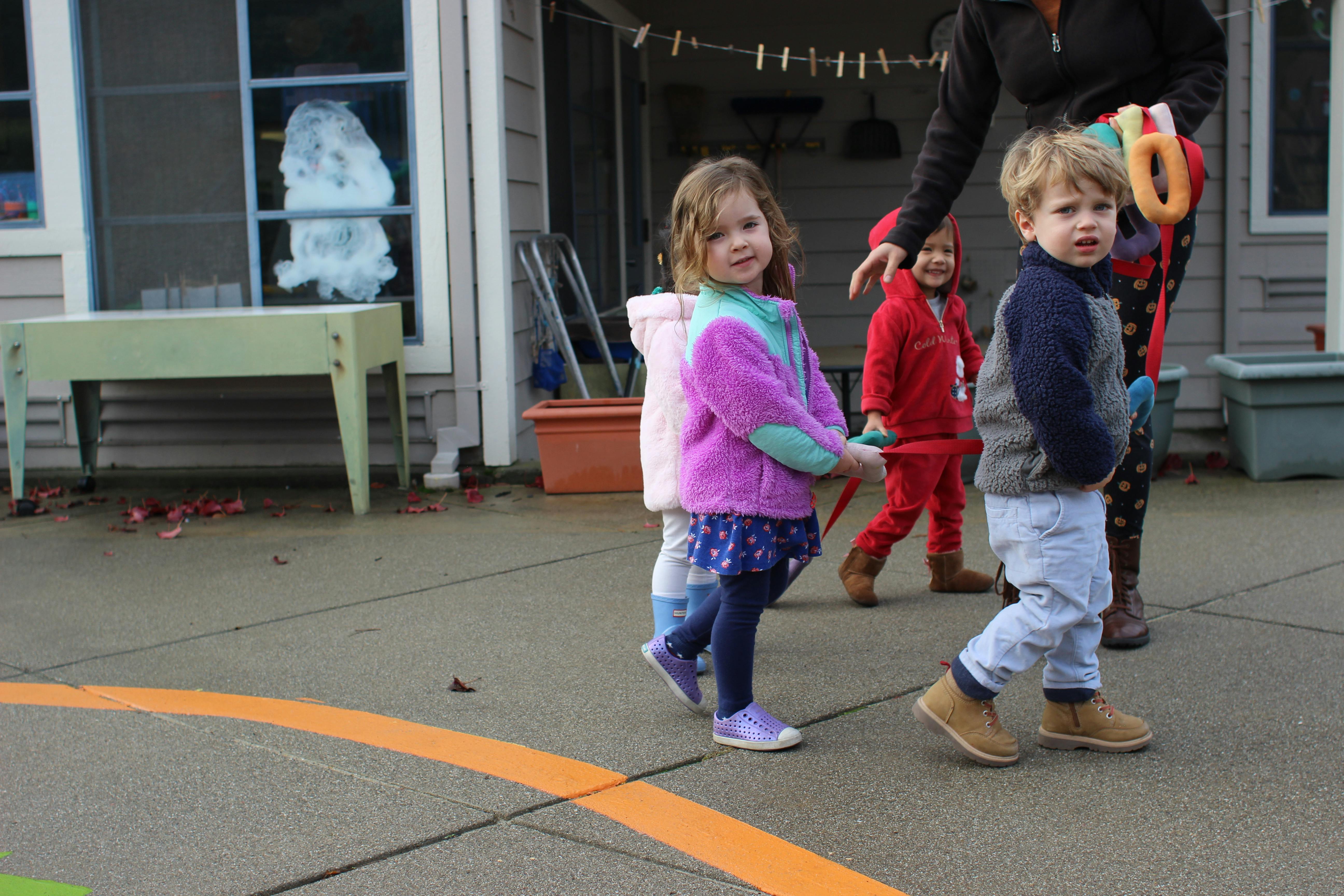 Three children walking outdoors with an adult