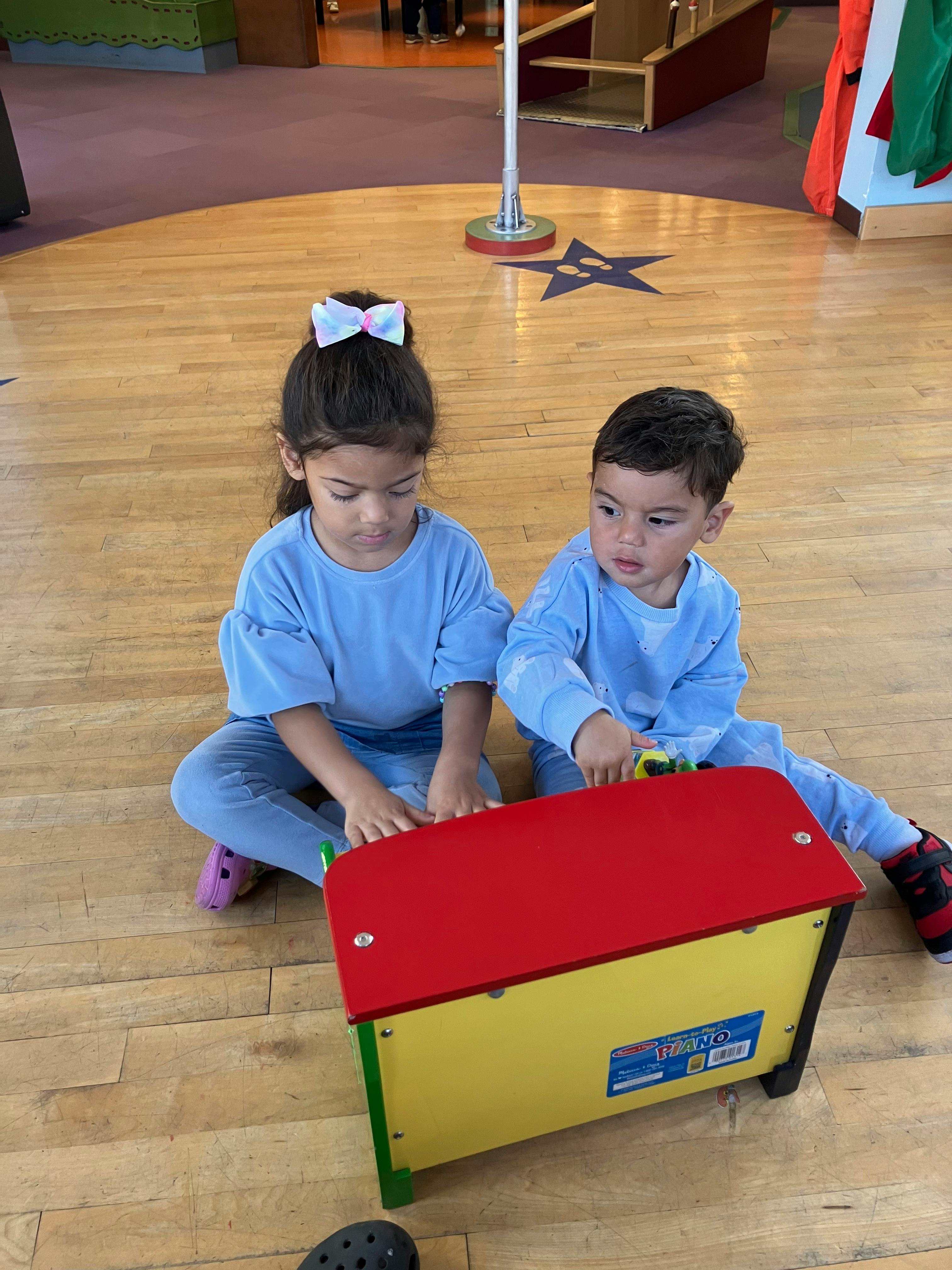 Two children sitting on the floor playing with a toy
