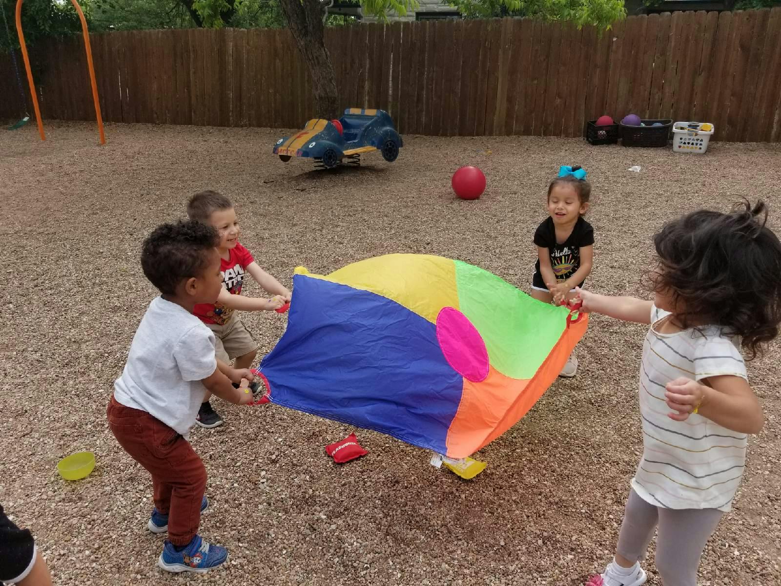 Children playing with a colorful parachute outdoors
