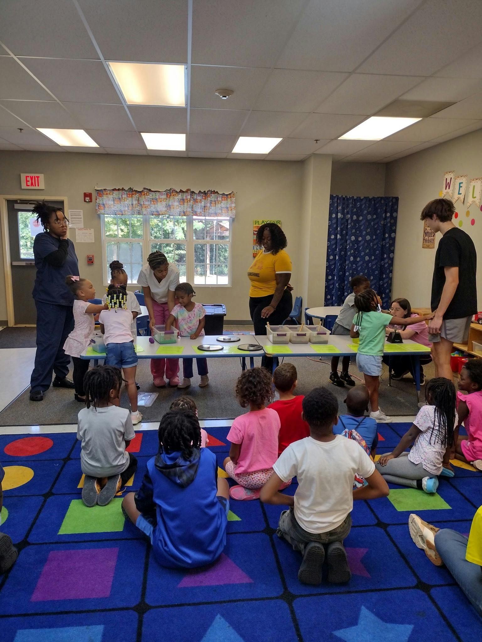 Adults and children gathered around tables in a classroom