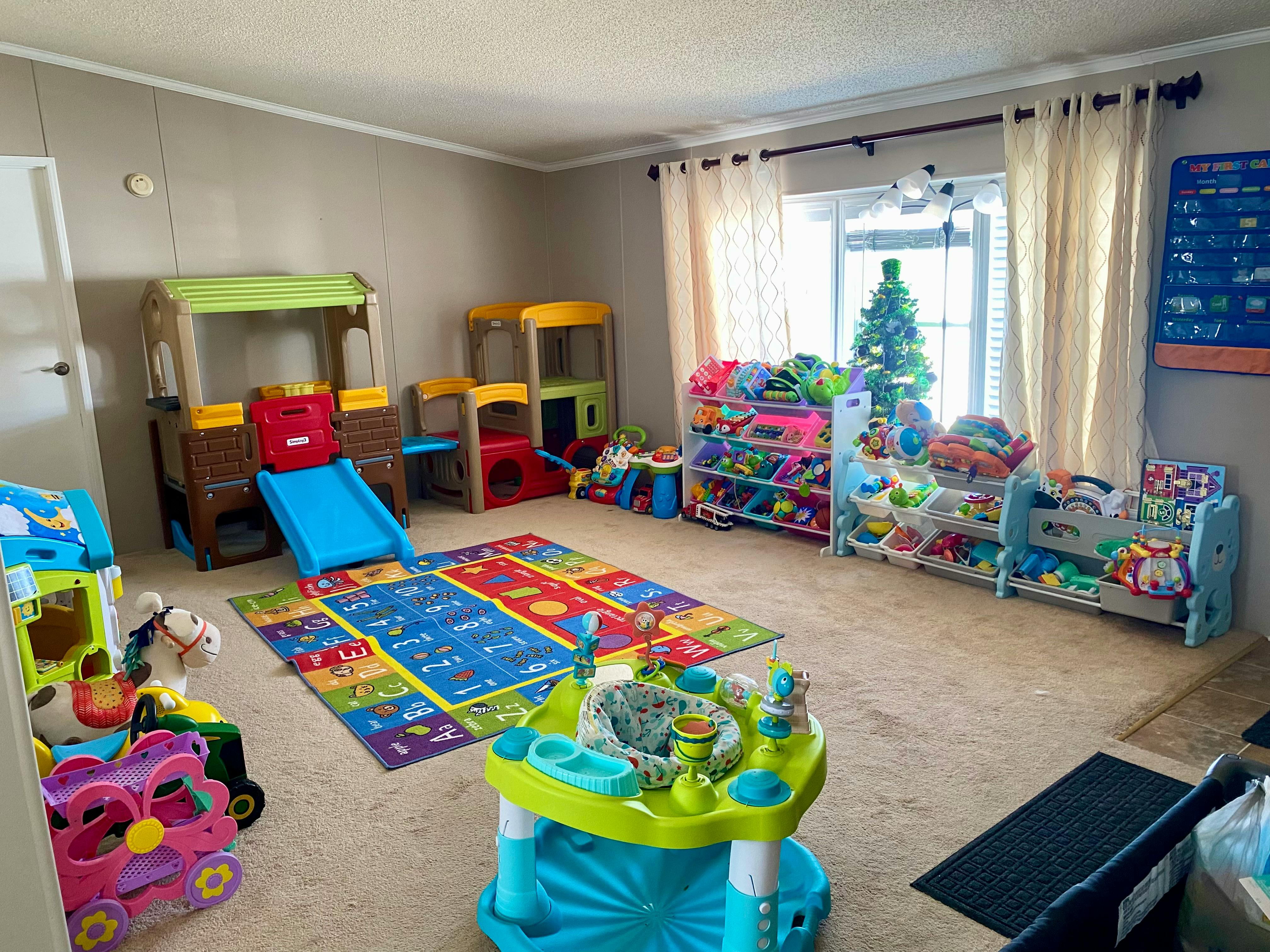 Playroom with colorful toys, play structures, and a rug