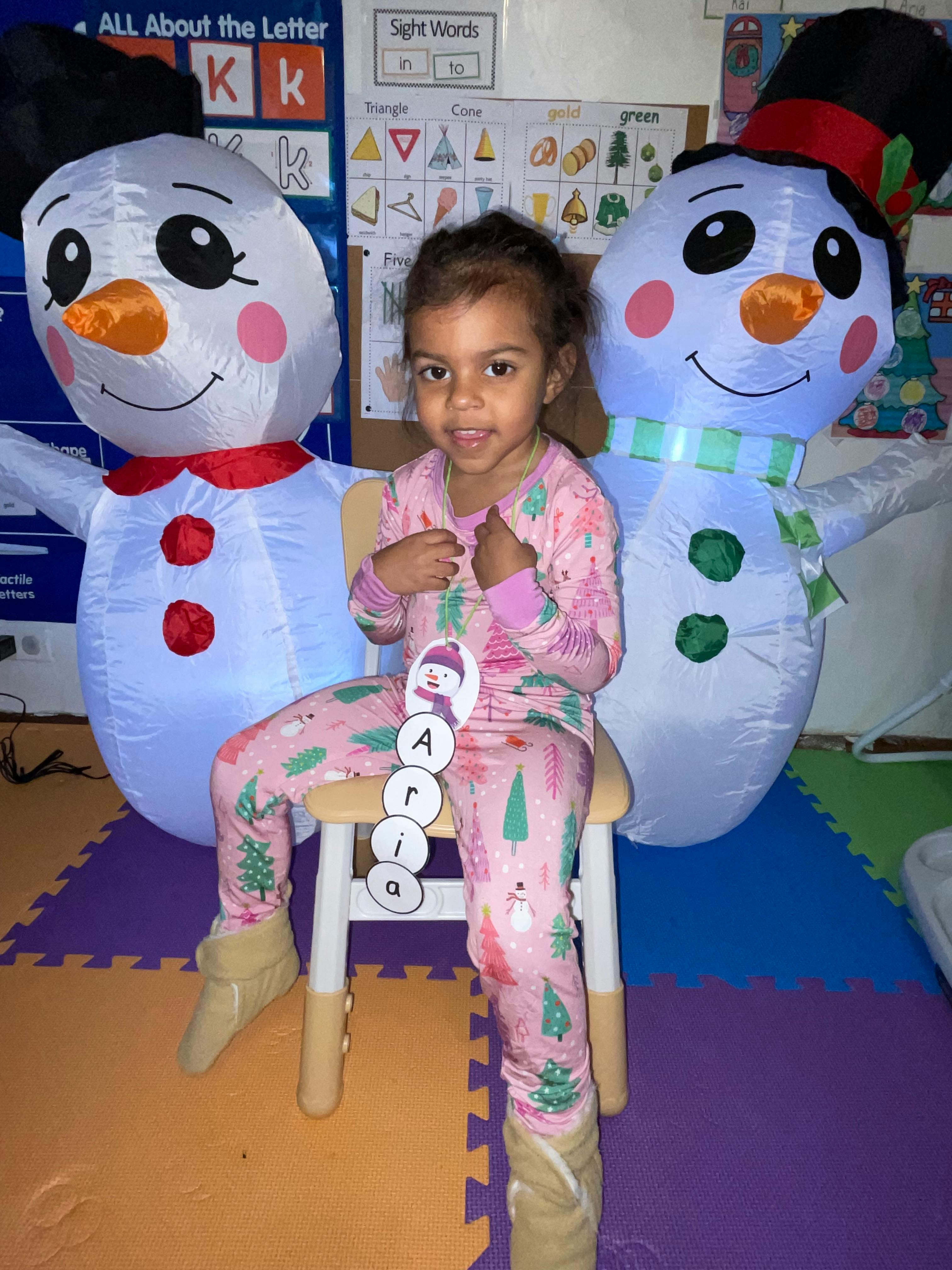 Child sitting on a chair between two inflatable snowmen