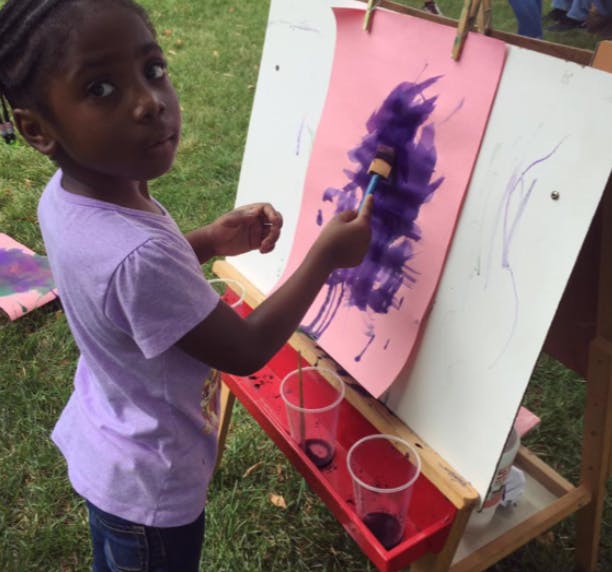 Child painting on an easel outdoors