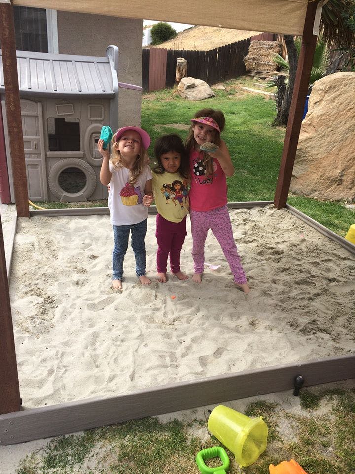 Three children standing in a sandbox
