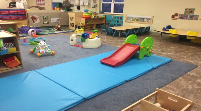 Playroom with a red slide on blue mats and various toys