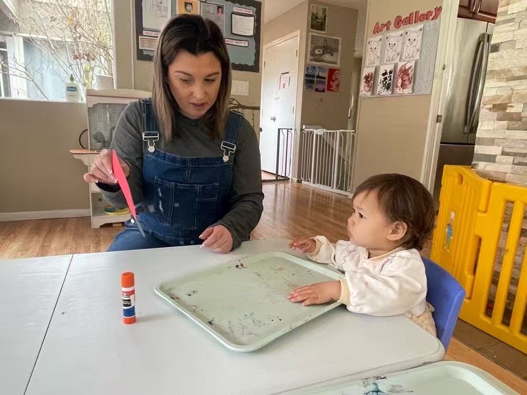 Person cutting red paper at a table with a child