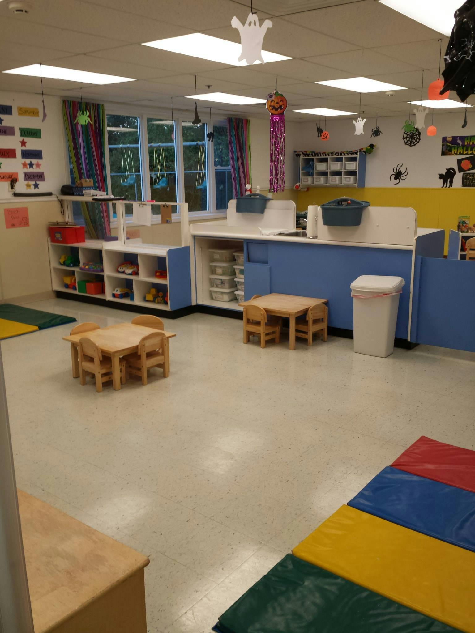 Classroom with small tables and chairs, storage shelves, and windows