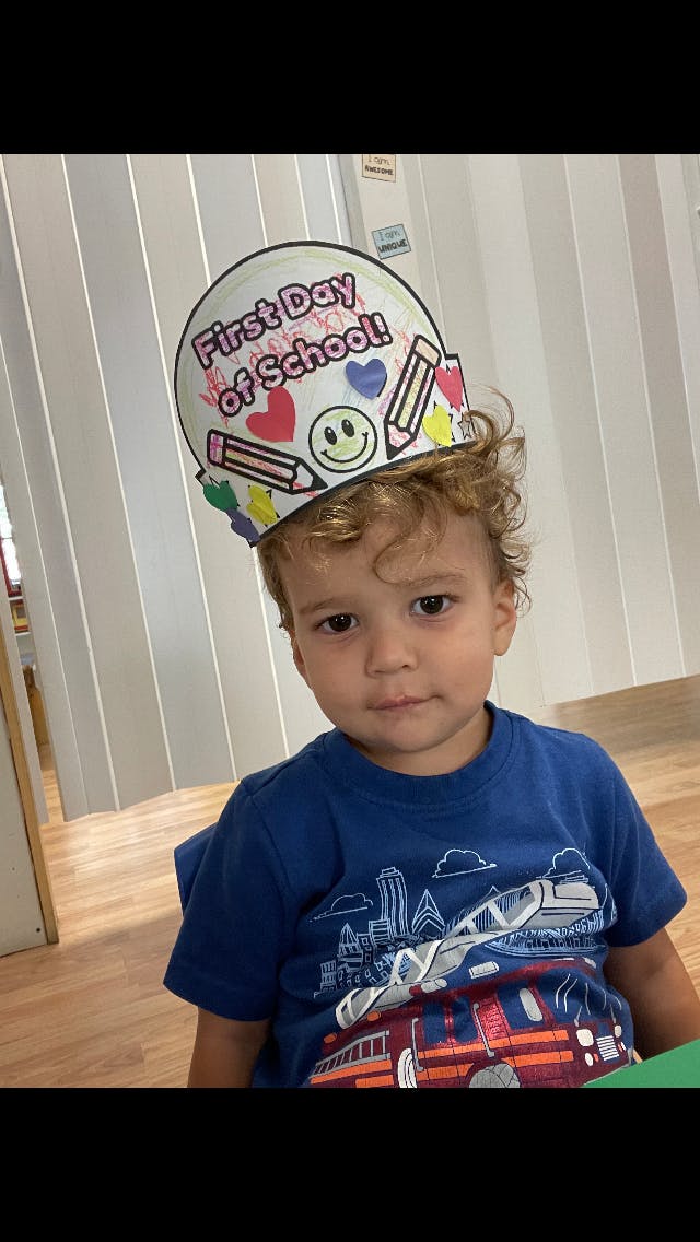 Child wearing a "First Day of School!" hat