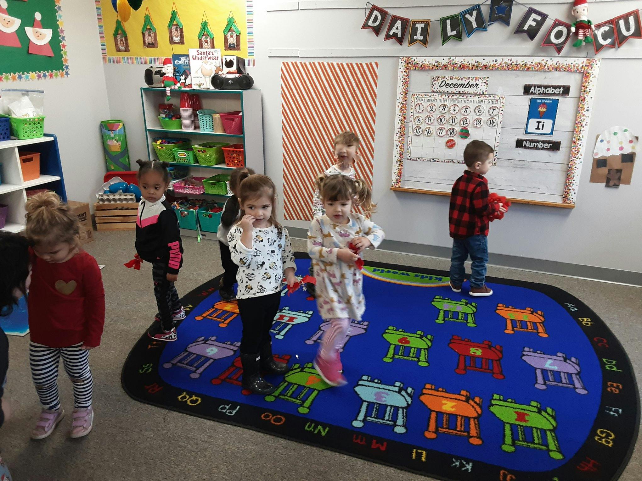 Children standing on a rug in a classroom