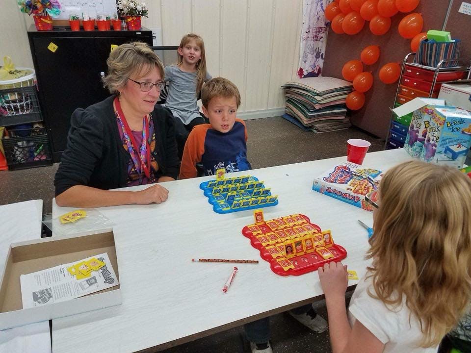 Adult and three children playing a board game at a table