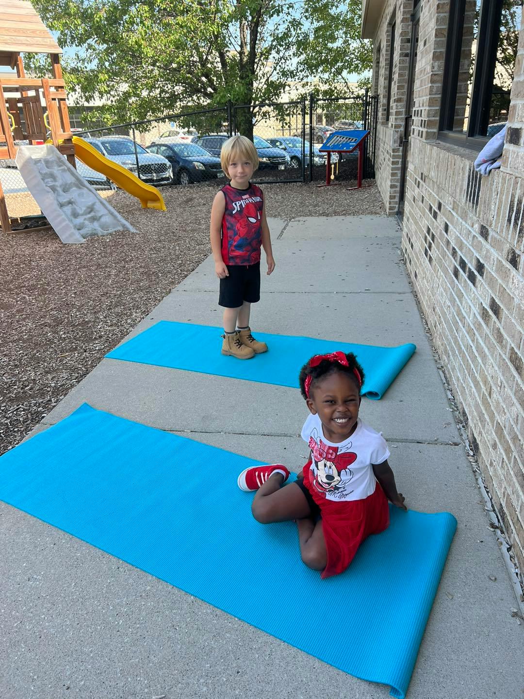 Two children on blue mats outdoors
