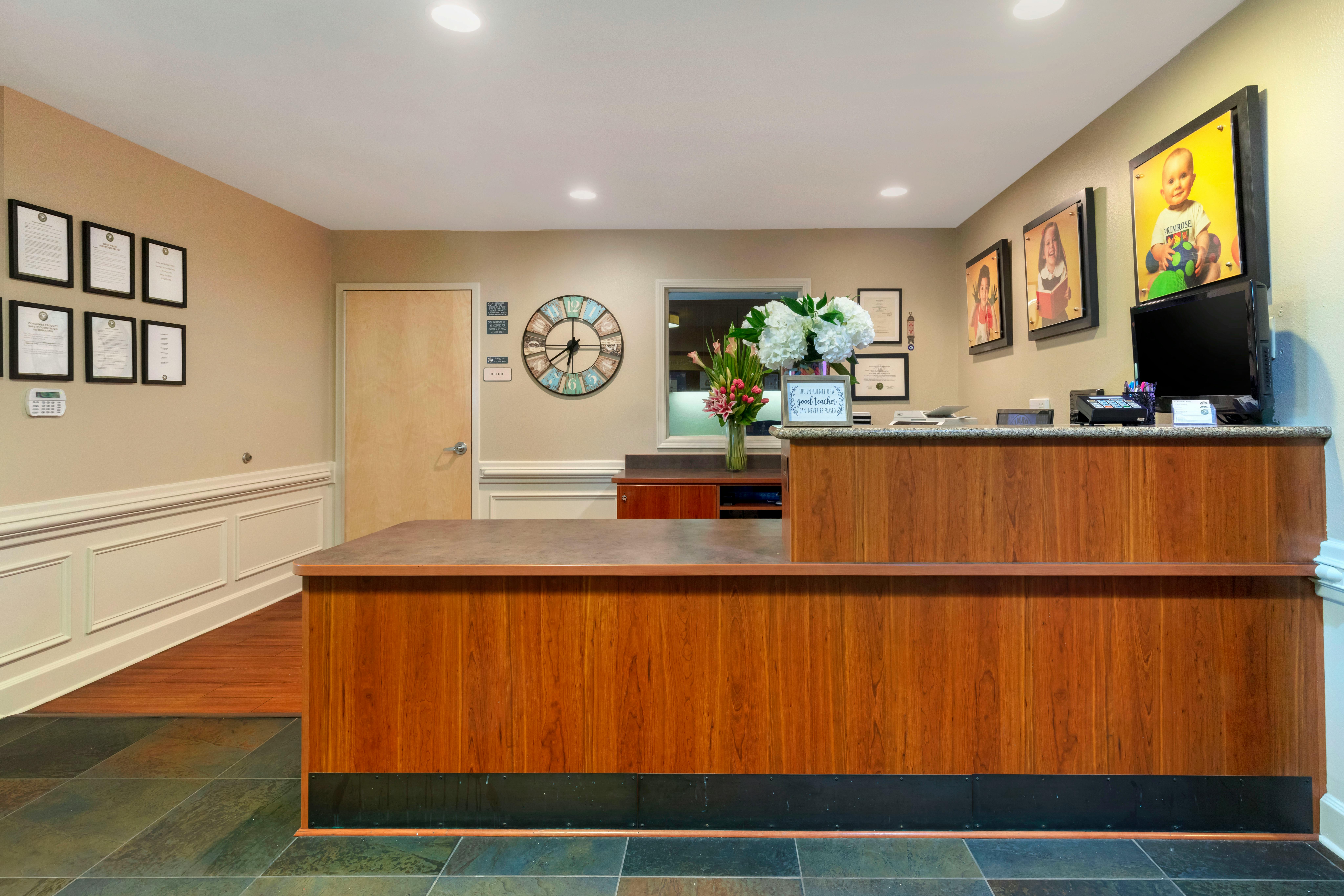 Reception desk with wood paneling and a dark countertop, floral arrangements, and wall decor