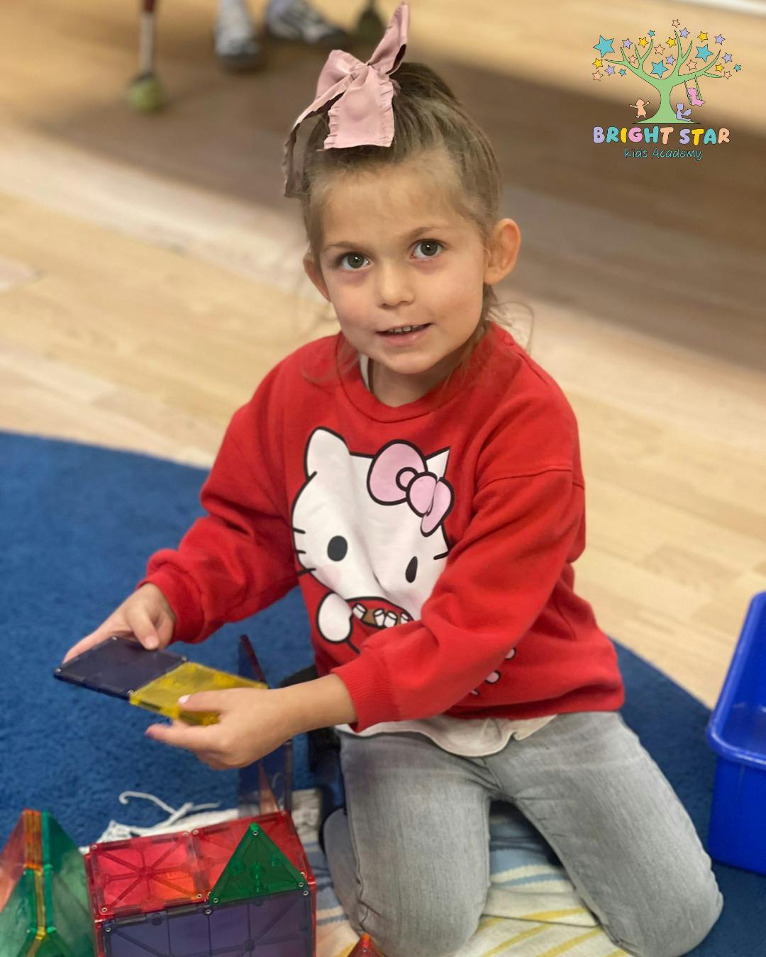 Child kneeling and holding magnetic tiles