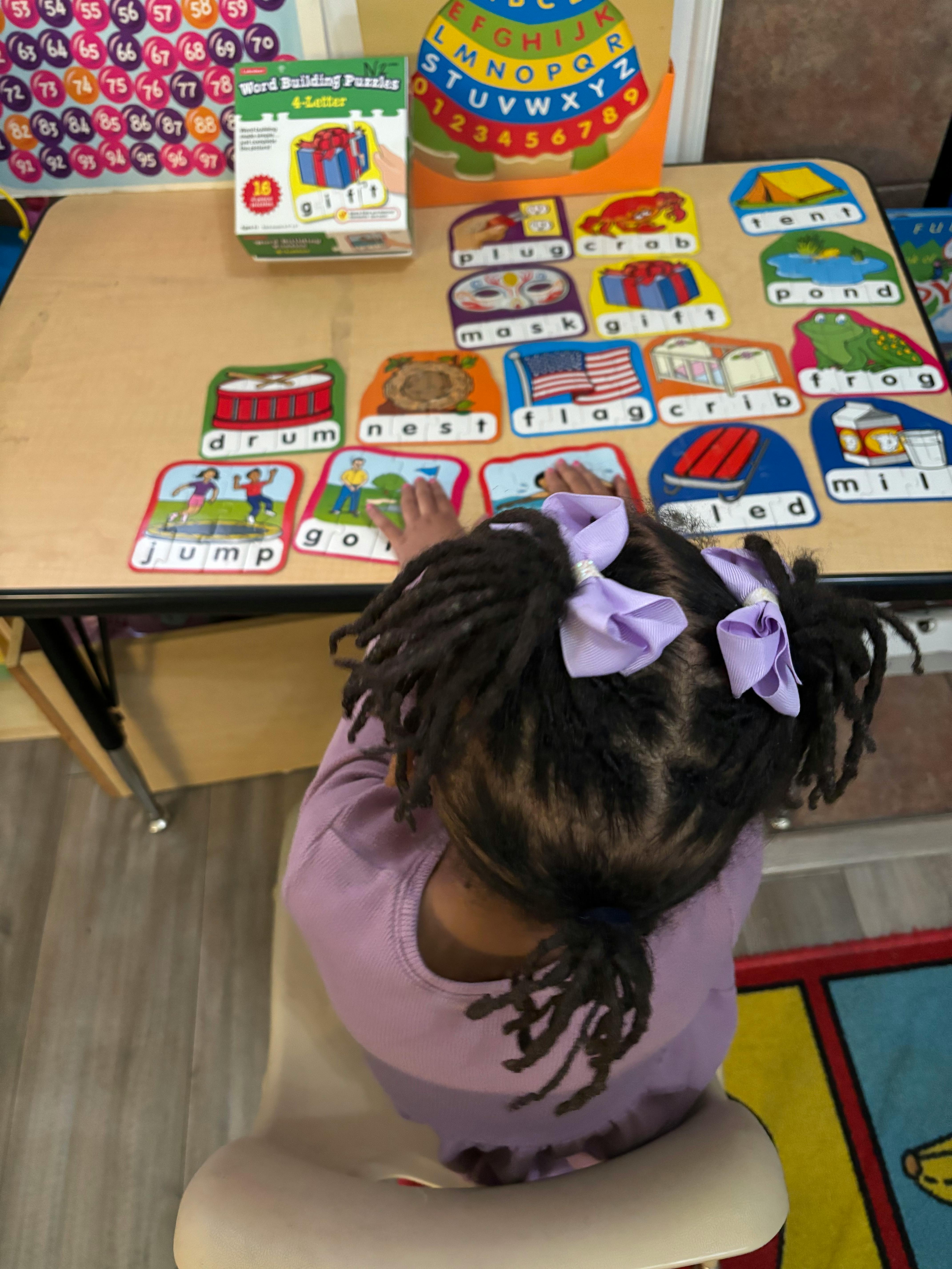 Child playing with word building puzzles on a table