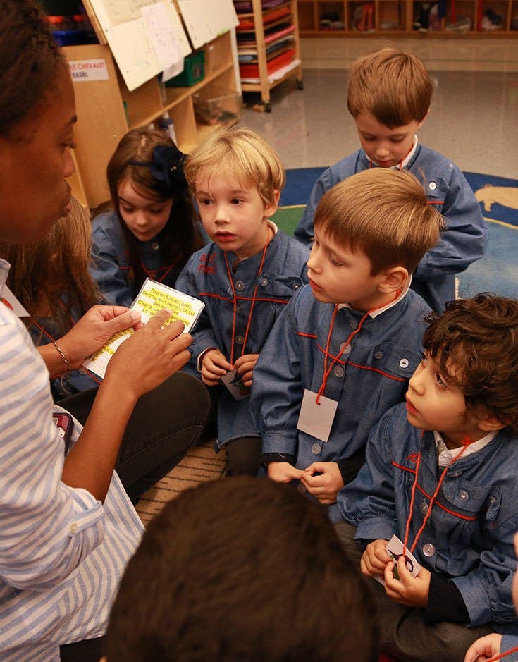 Adult showing a book to children in a classroom