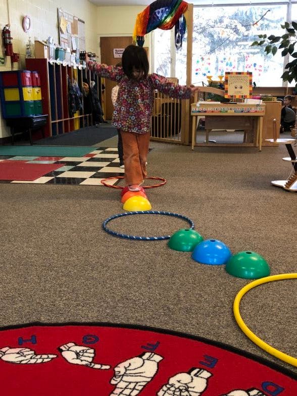Child balancing on a hula hoop in a classroom