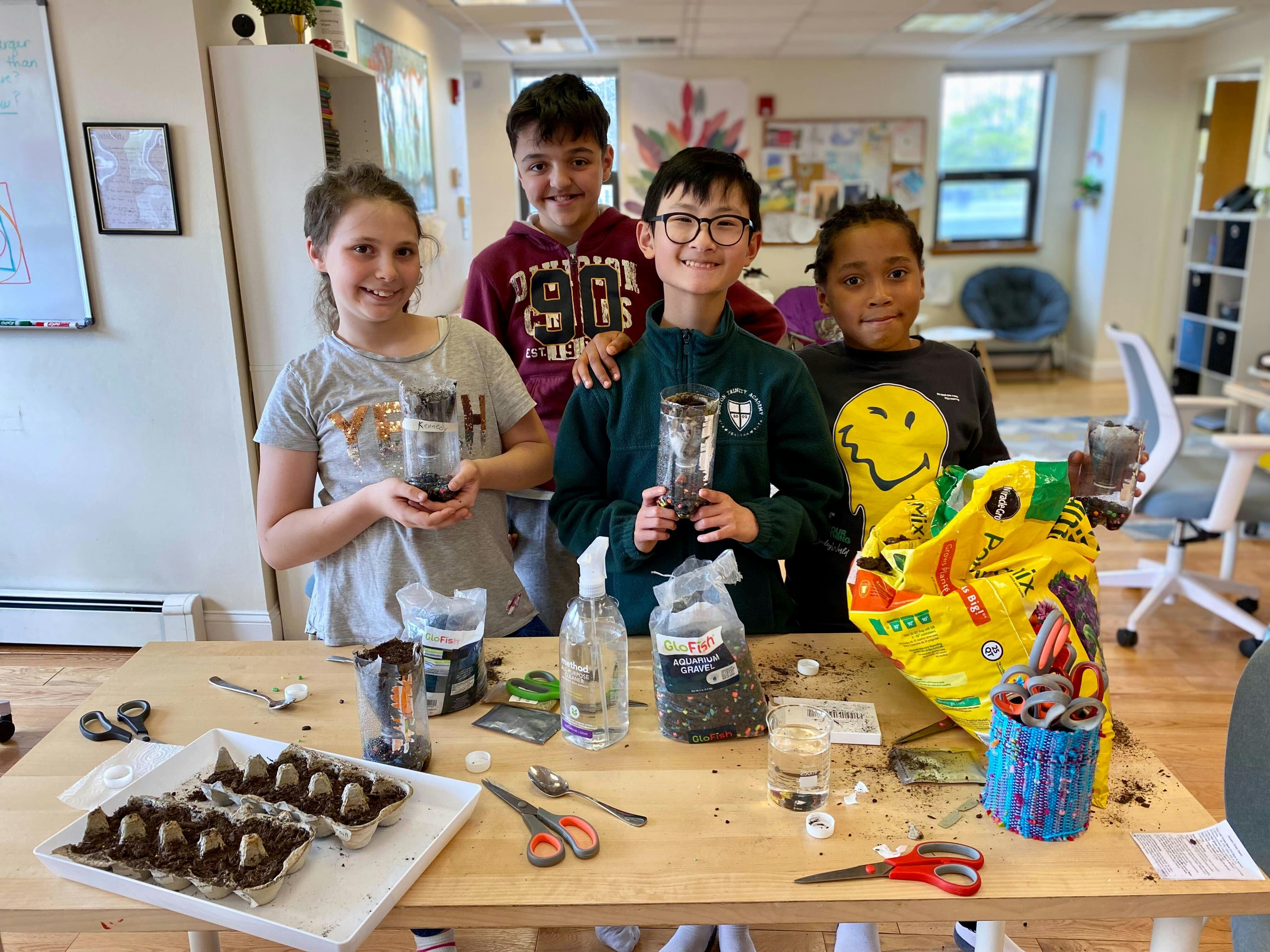 Four children standing around a table with gardening supplies
