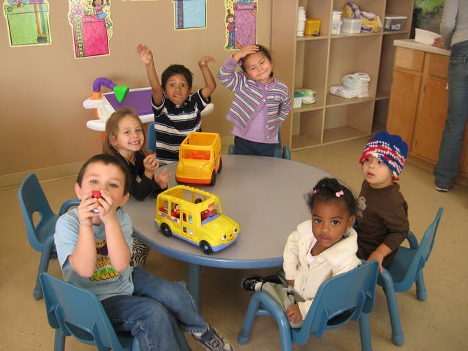 Children sitting around a table with toy buses
