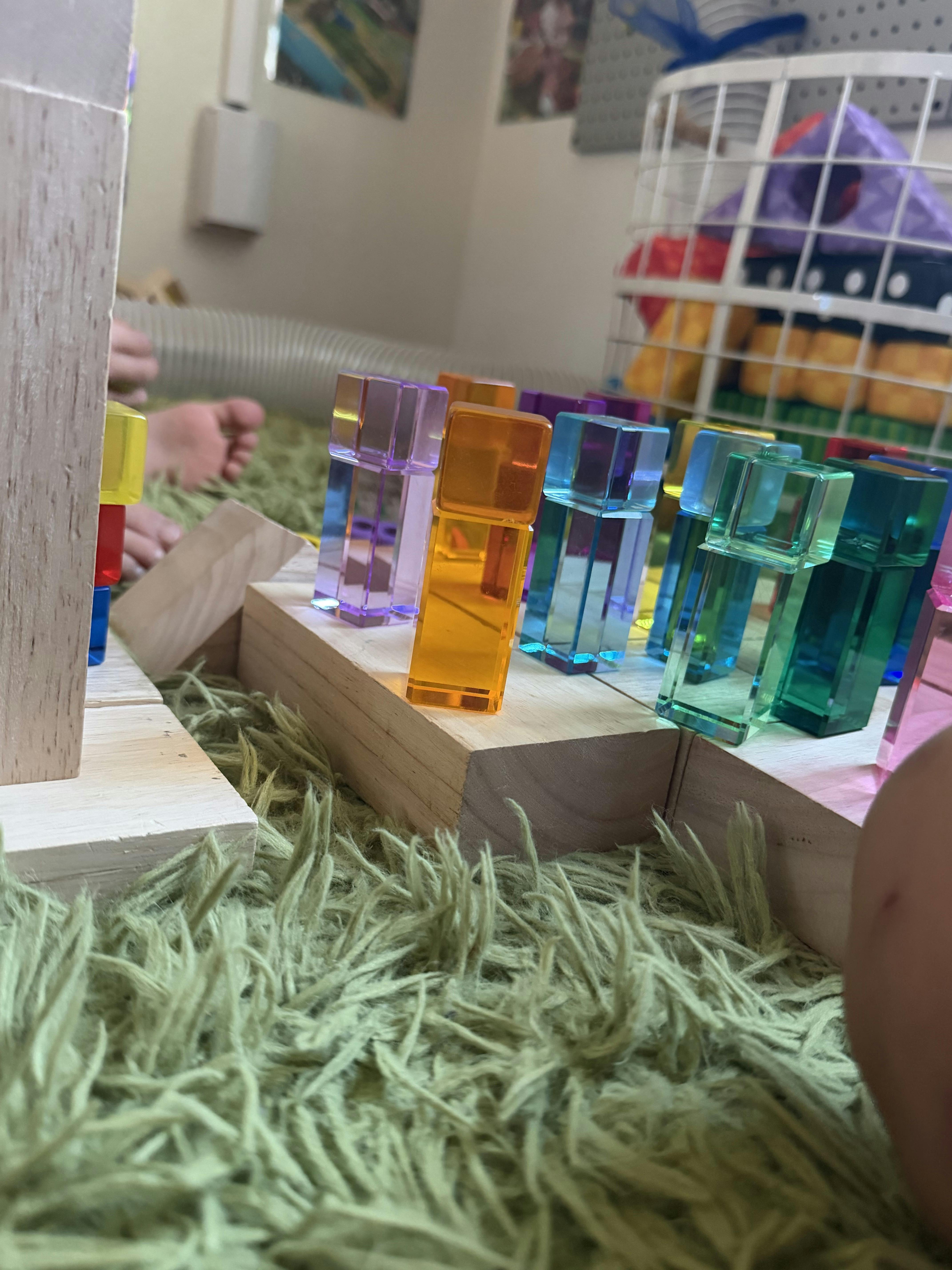 Child playing with colorful translucent building blocks on a rug