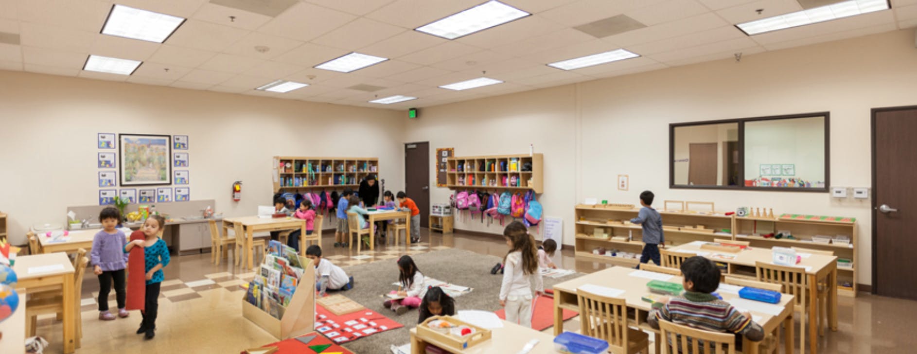 Children in a classroom with tables and shelves