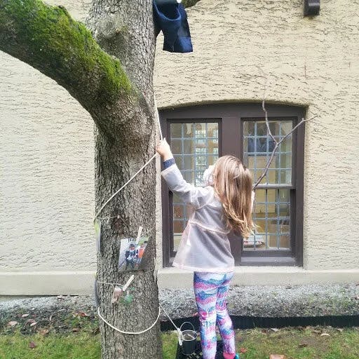 Child standing on a bucket, holding a rope attached to a tree