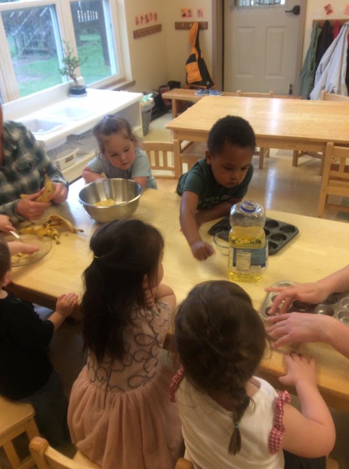 Children and an adult at a table preparing food