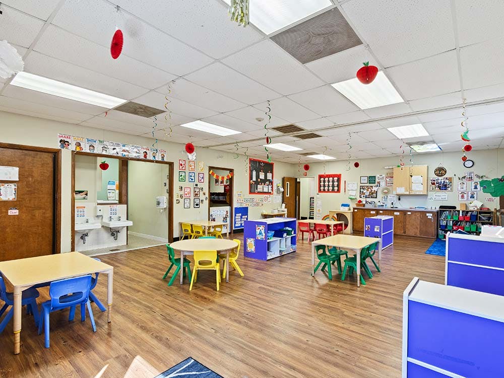 Empty colorful children's classroom with small tables and chairs