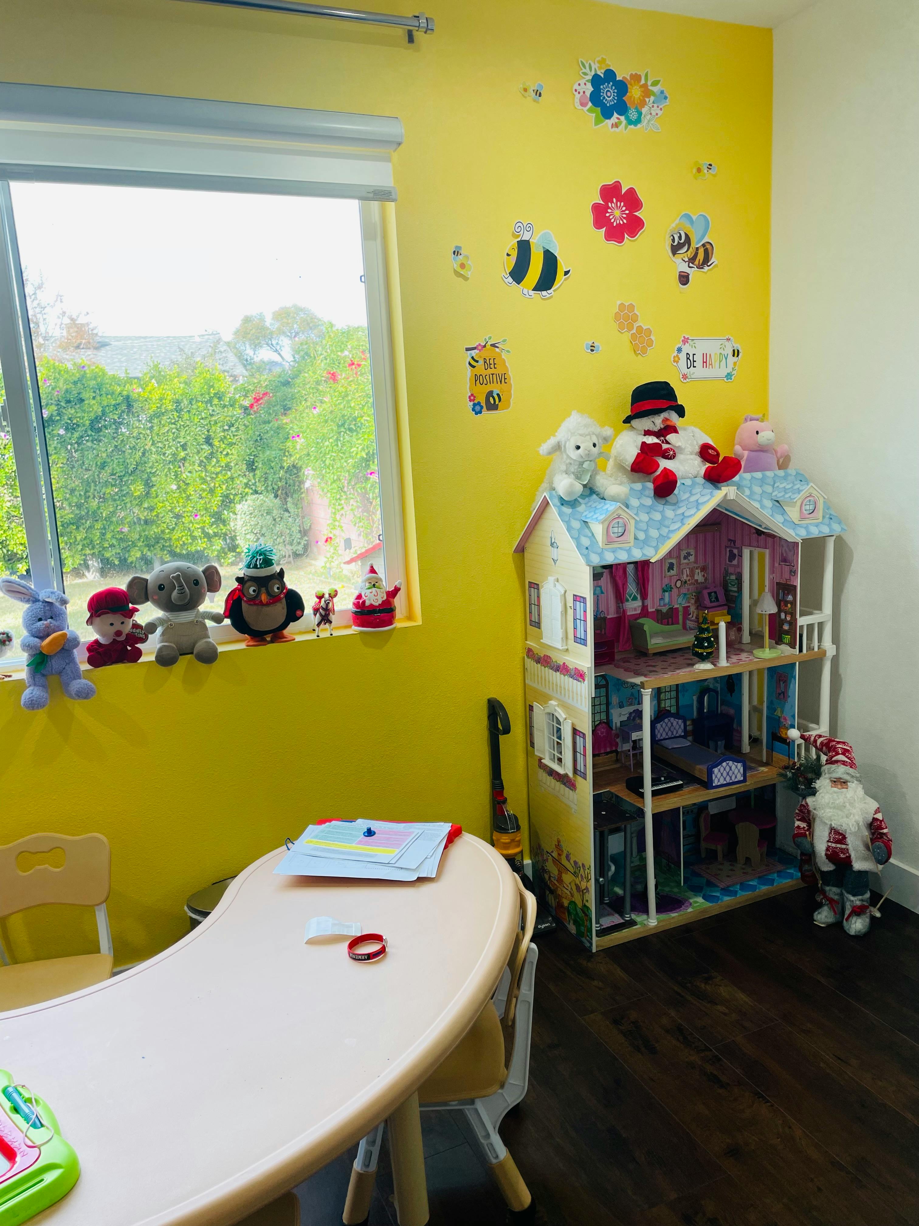 Playroom with a dollhouse, stuffed animals, and a small table and chairs