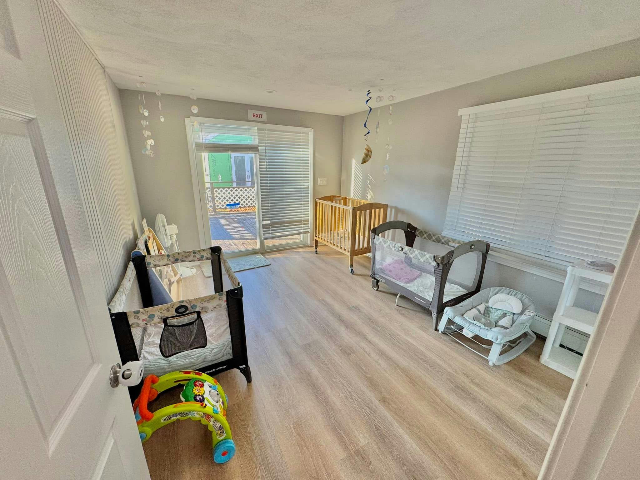 Nursery room with two cribs and a baby bouncer