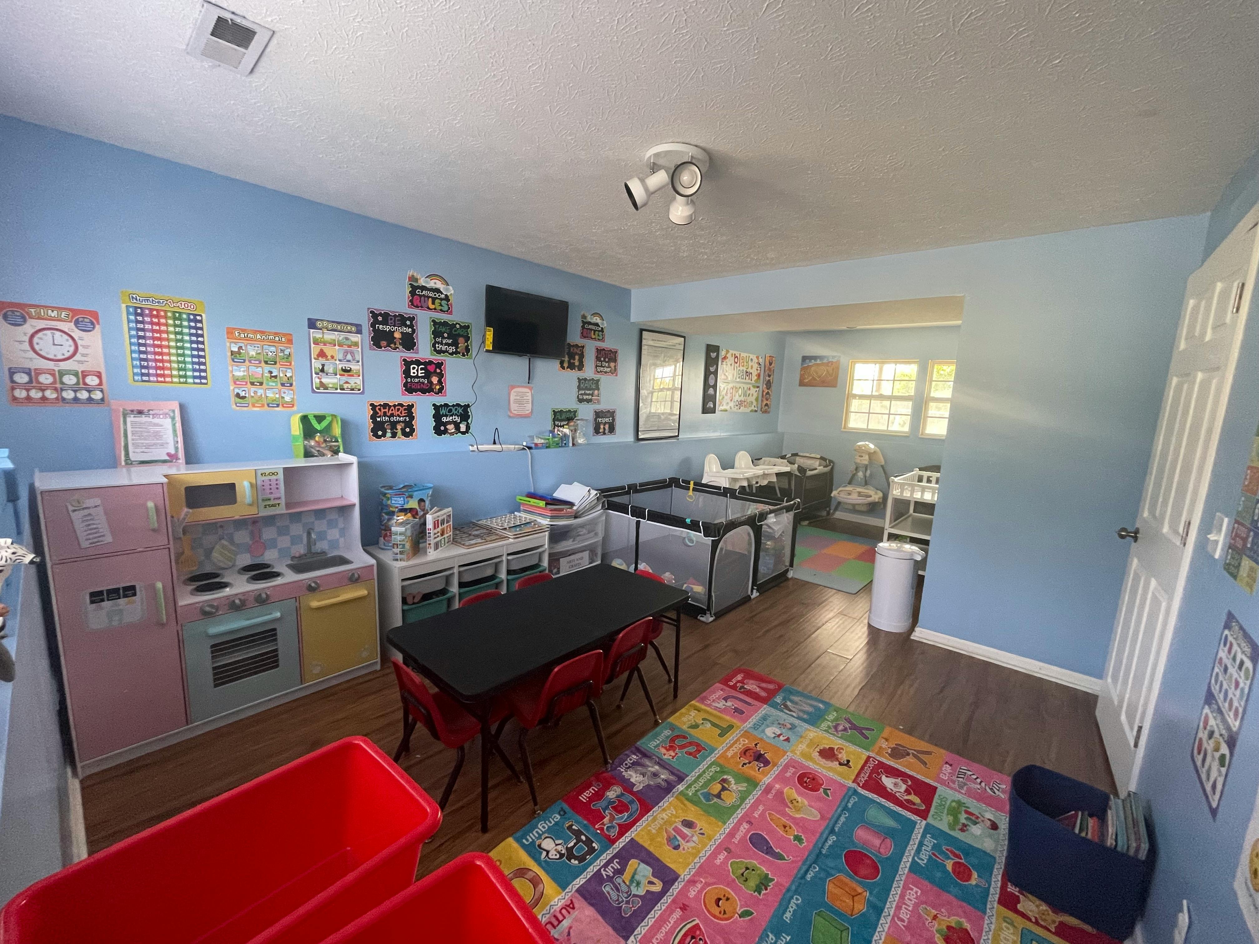 Playroom with toy kitchen, small tables and chairs, and playpens