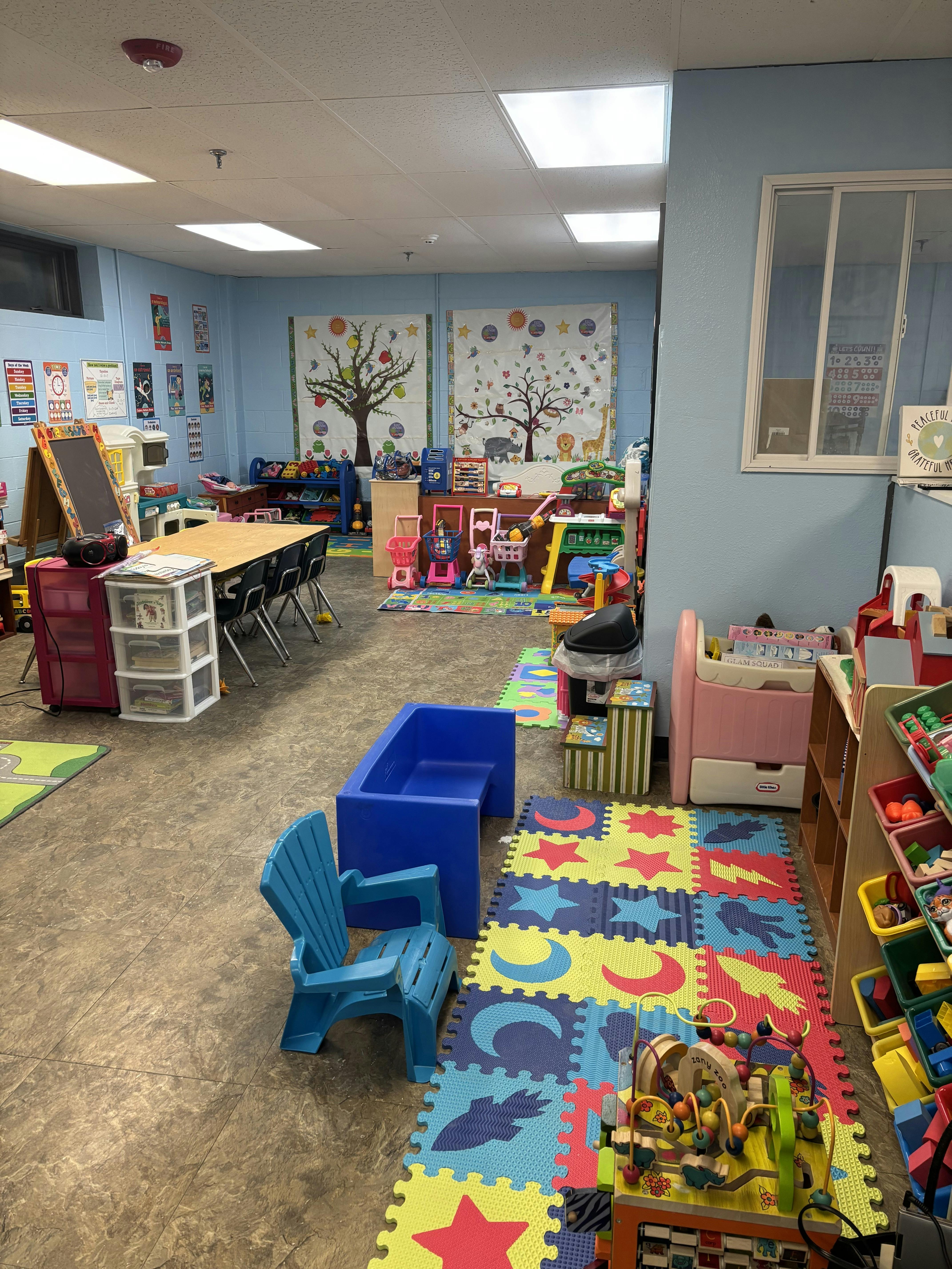 A colorful classroom with various toys, puzzles, a table, and chairs