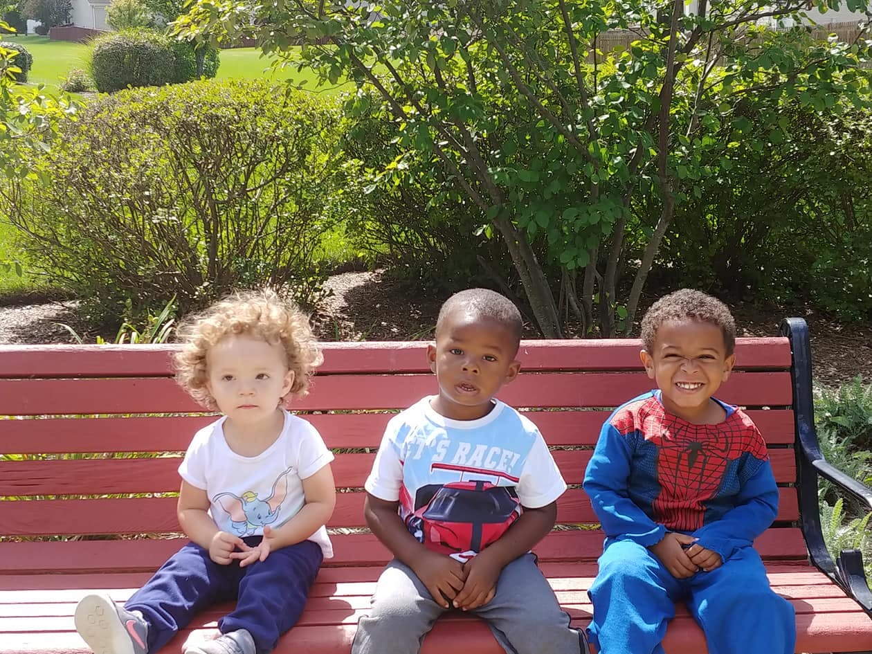 Three children sitting on a park bench