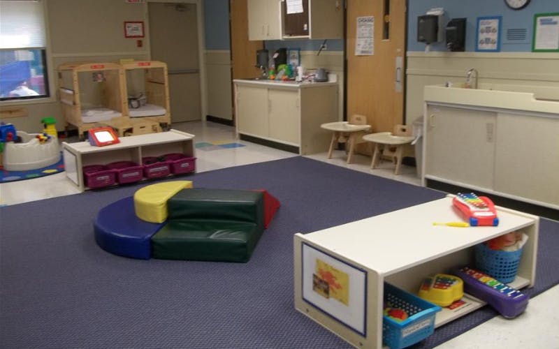 Childcare room with cribs, changing table, and play mats