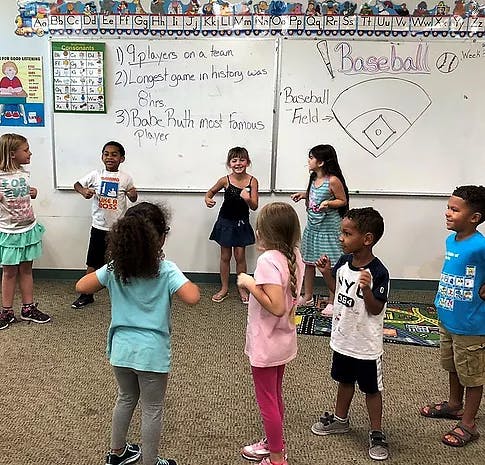 Children standing in a classroom with a whiteboard behind them