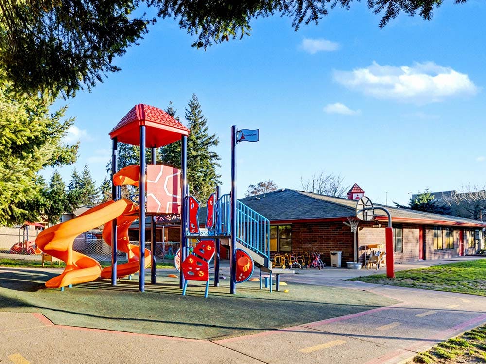 Playground with slides and play structure next to a building