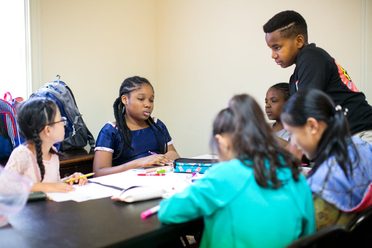 Adult and children gathered around a table with papers and art supplies