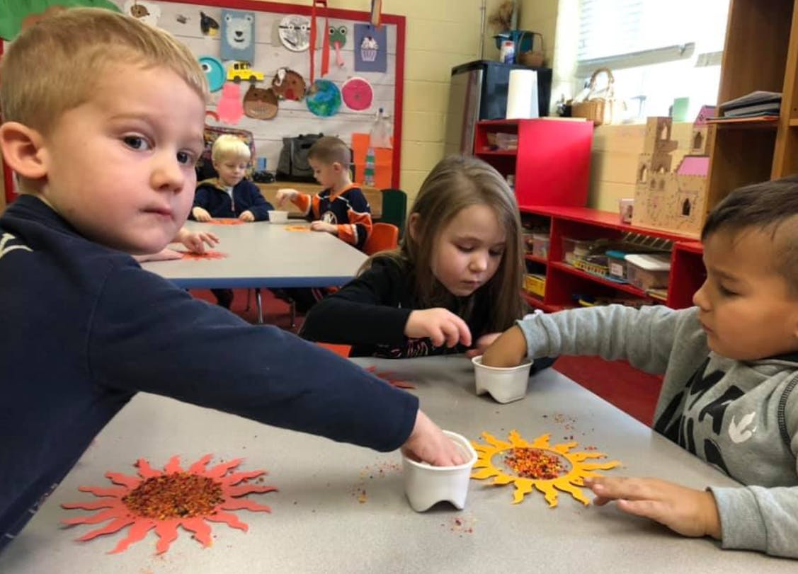 Children doing crafts at a table in a classroom