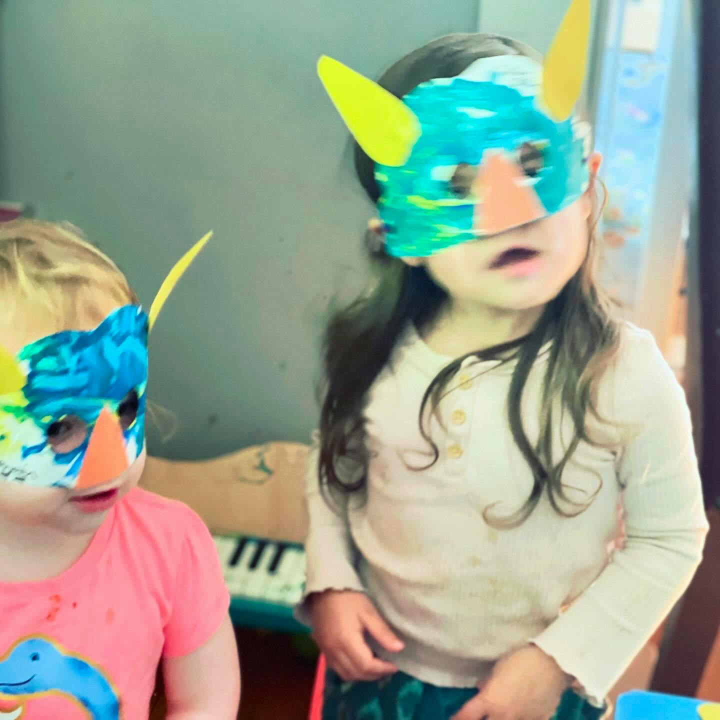 Two children wearing colorful masks with horns
