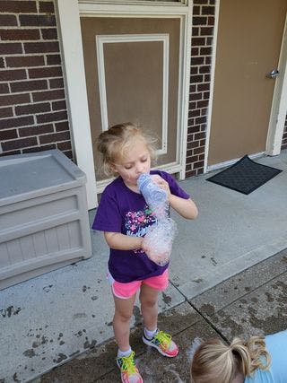 Child blowing bubbles from a bottle