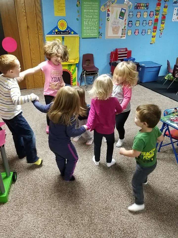 Children holding hands in a circle in a classroom