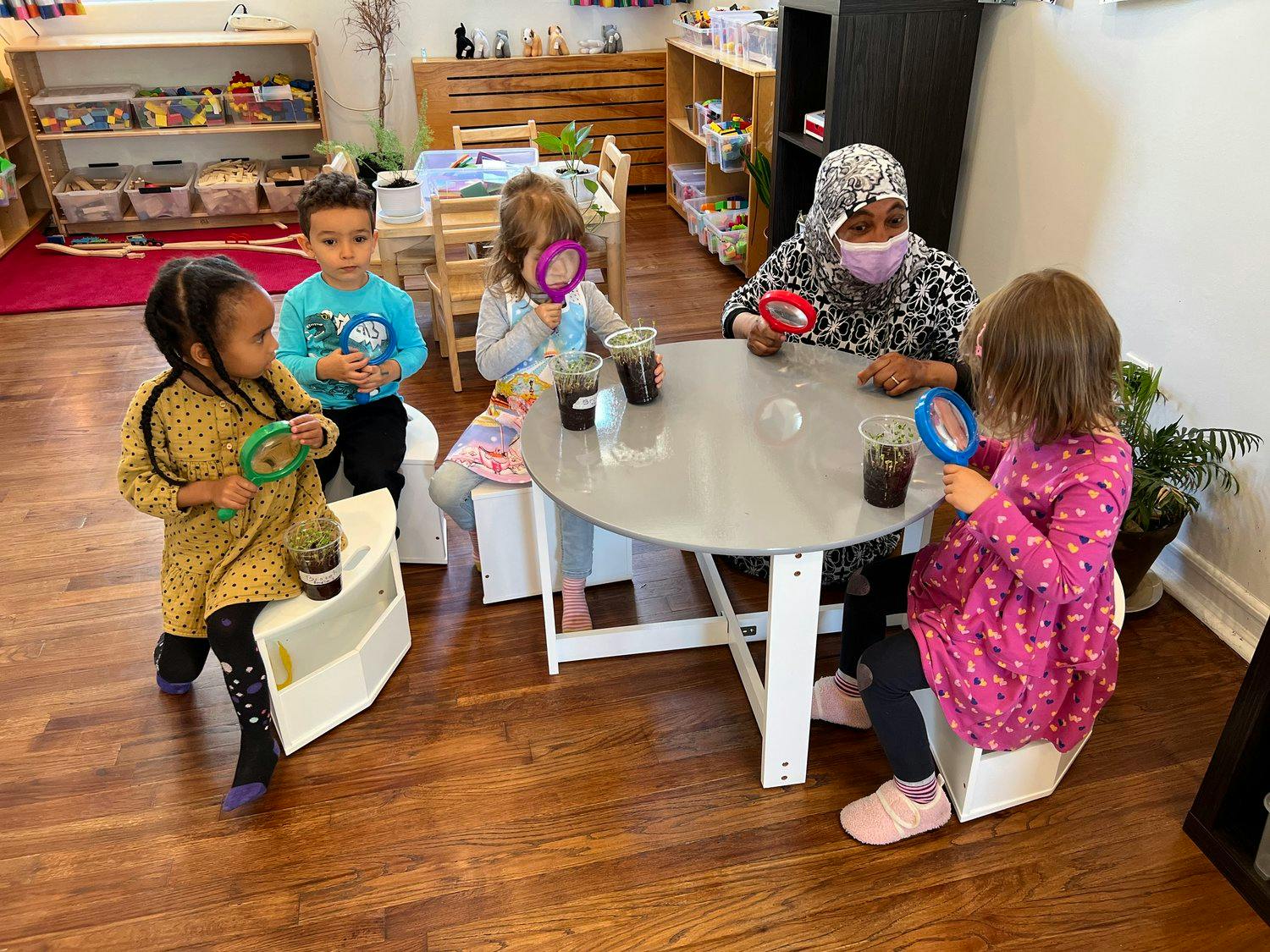 Adult and children at a table with magnifying glasses
