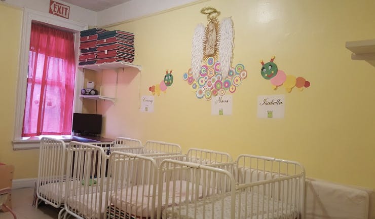 Multiple cribs in a room with yellow walls and colorful decorations
