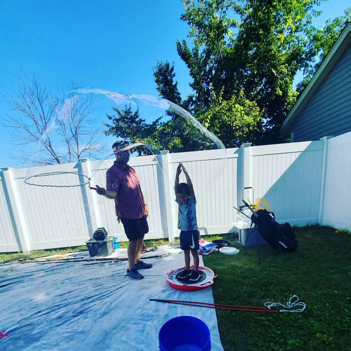 Person and child making large bubbles outdoors