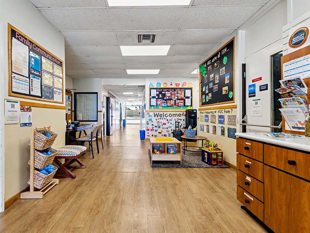 Hallway in an institutional building with noticeboards and children's activity area
