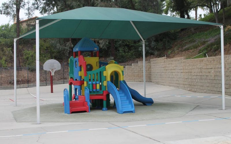 Playground with colorful slides under a green shade canopy