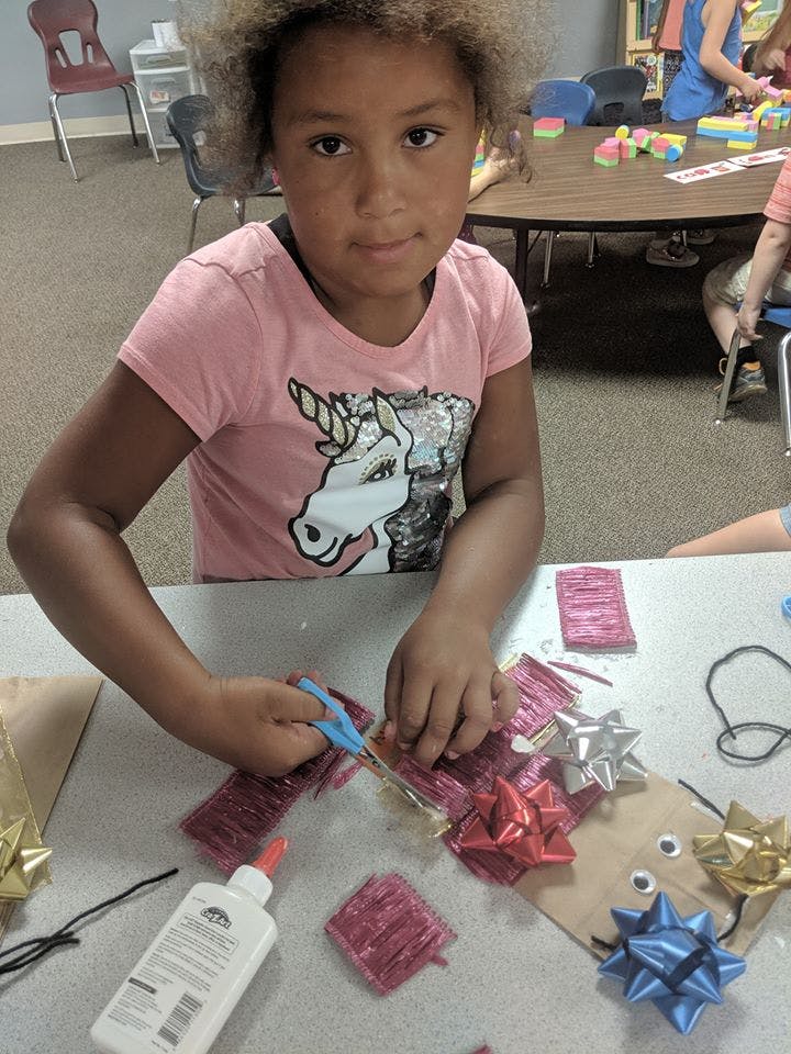 Child cutting craft materials with scissors