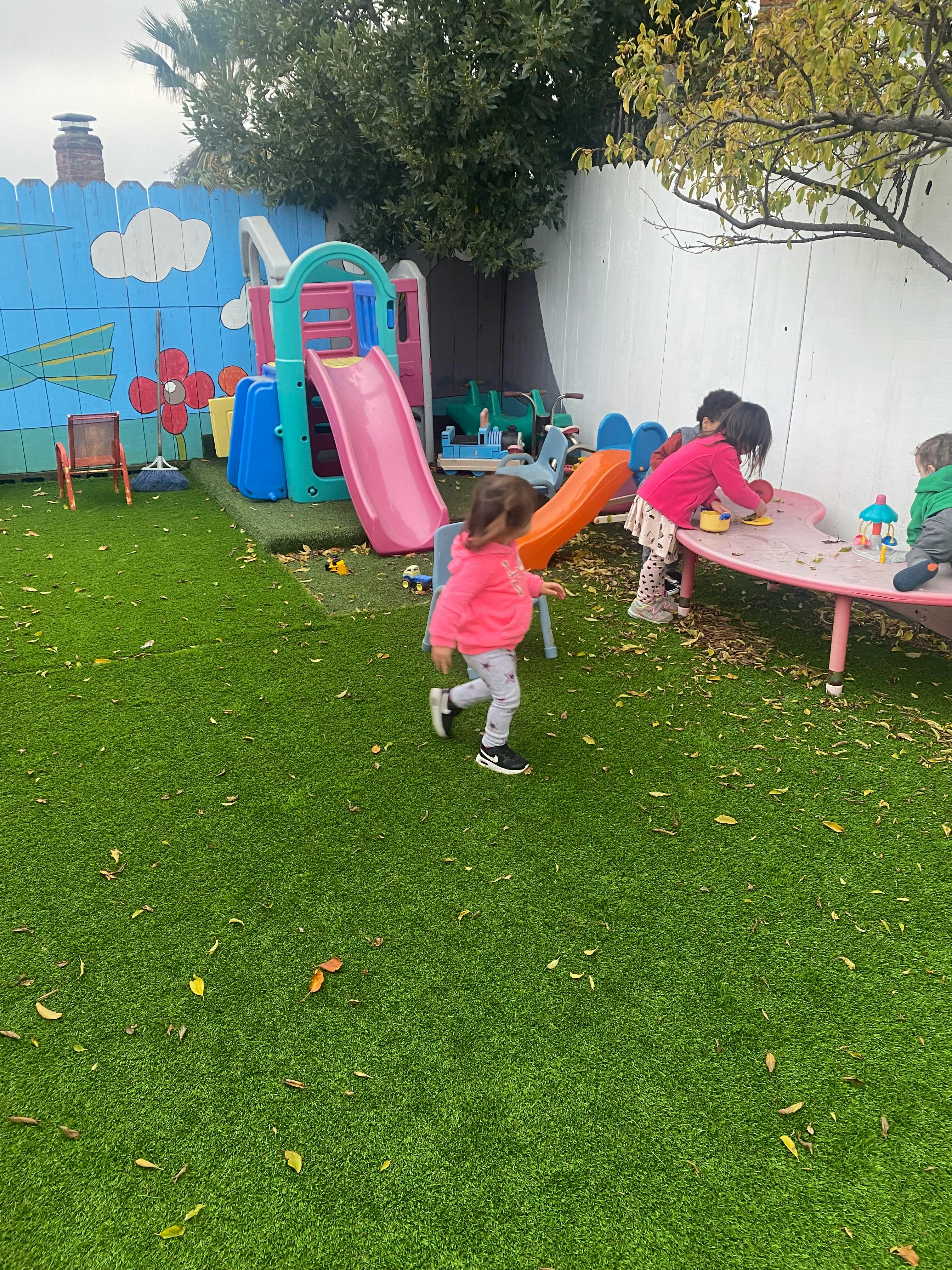 Children playing in a backyard with a slide and table